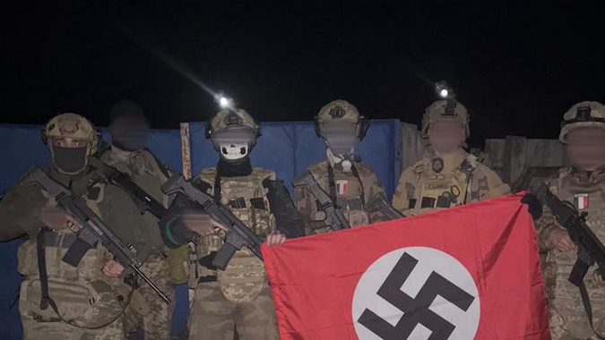 Несколько французских добровольцев, воюющих на Украине, позируют с флагом, на котором изображена свастика.