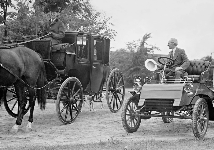Американец Генри Форд сидит в старом автомобиле Ford «Модель А» и отдает честь конной повозке. «Модель А» — первый автомобиль компании Ford Motor Company, основанной в 1903 году. Фото: Scherl/Global Look Press
