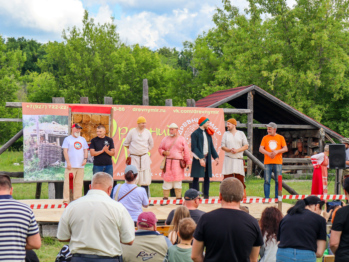 Руководитель парка (в белой шапке) представляет участников фестиваля и рассказывает о предстоящих активностях. С ним на сцене основные участники и организаторы.
